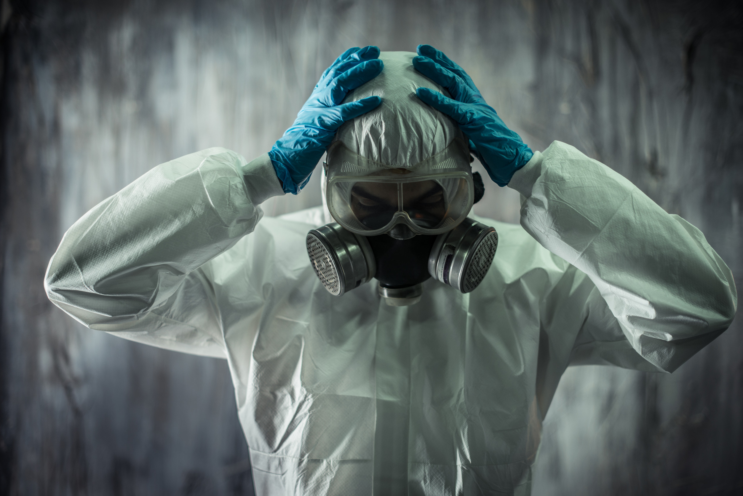 Personne en combinaison protectrice et masque respiratoire.